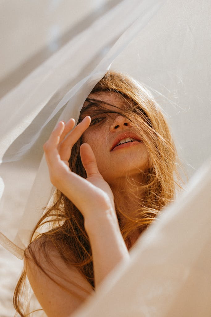 A serene portrait of a woman with flowing hair in a gentle, sunlit setting.